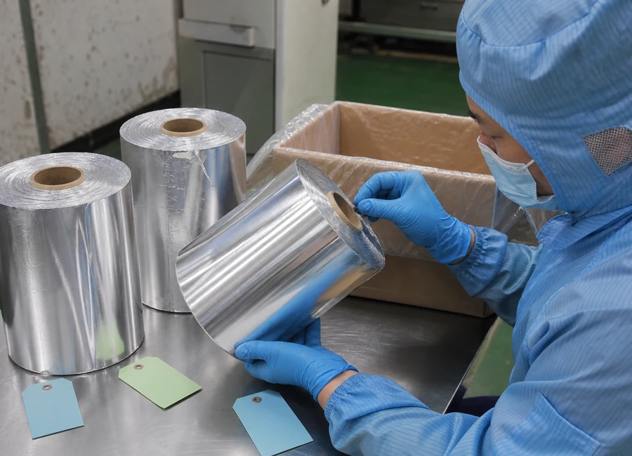 Worker inspecting aluminum foil rolls